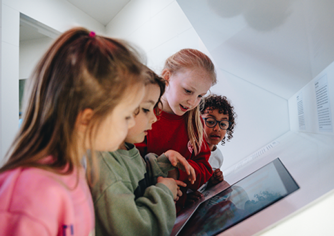 4 kinderen kijkend naar museumspel op een scherm