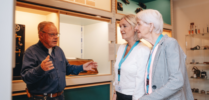 Headerafbeelding FAQ: medewerker techniekmuseum helpt bezoekers in het museum op weg.